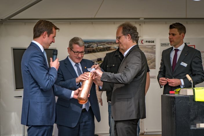 Thomas Heinicke, Logistikleiter MediaMarktSaturn Deutschland (2.v.r.) und Landrat Dr. Klaus Effing (2.v.l.) befüllen die Zeitkapsel.